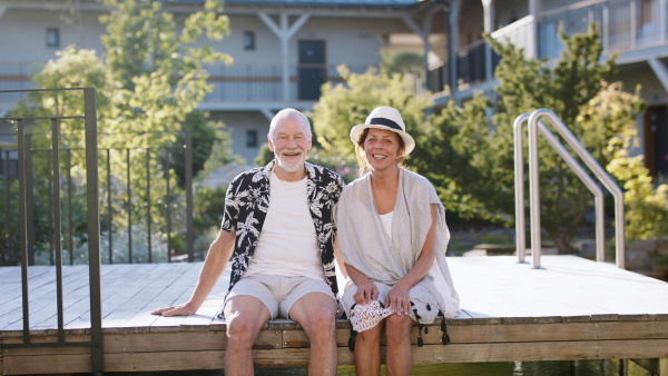 Portrait of senior couple resting outdoors on holiday, looking at camera.