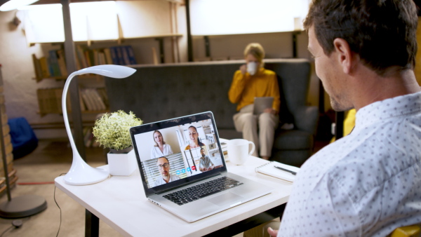 Mature businessman with laptop working indoors in home office, business call concept.