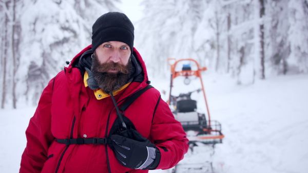 Paramedic man from mountain rescue service with walkie talkie outdoors in a winter in forest.