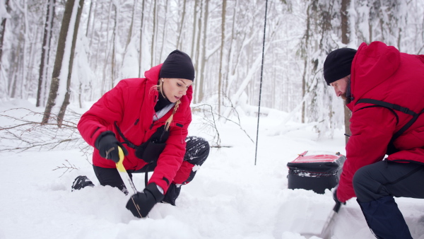 Mountain rescue service on operation outdoors in winter in forest, looking for burried person in snow.