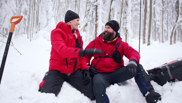 Mountain rescue service on operation outdoors in winter in forest, celebrating and looking at camera.