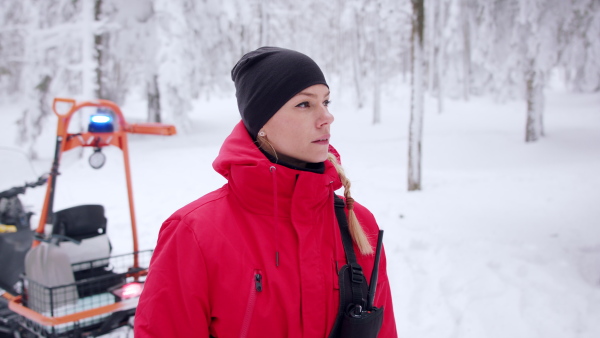 Paramedic woman from mountain rescue service with walkie talkie outdoors in a winter in forest.