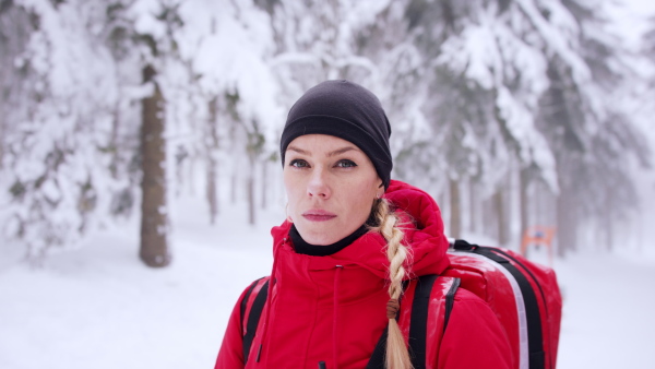 Paramedic woman from mountain rescue service with walkie talkie outdoors in a winter in forest.