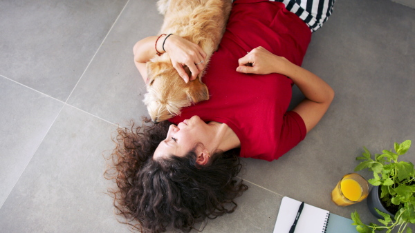 Top view of happy woman with pet dog lying indoors at home, relaxing.