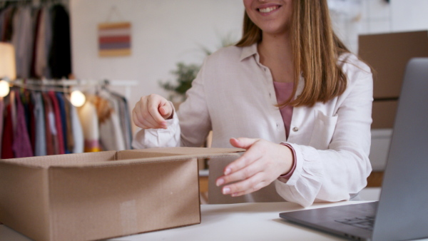 Unrecognizable young woman dropshipper with laptop working at home, coronavirus concept.