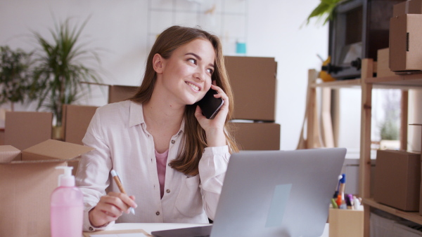 Young woman dropshipper working at home and having a call, coronavirus concept.