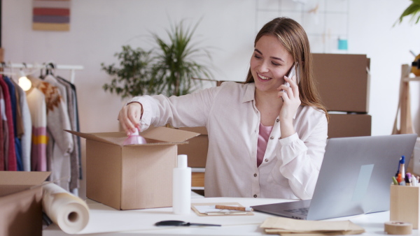 Young woman dropshipper working at home and having a call, coronavirus concept.