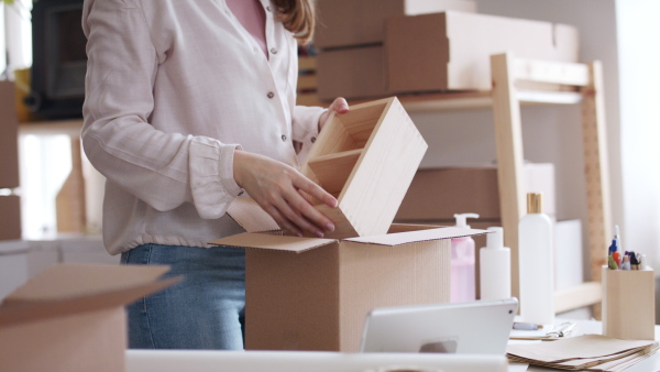 Unrecognizable young woman dropshipper with tablet working at home, coronavirus concept.