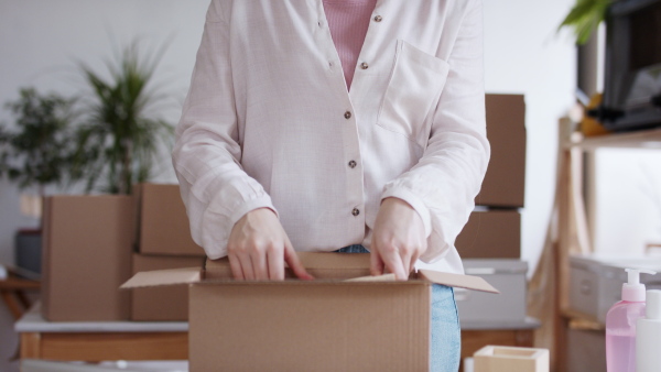 Unrecognizable young woman dropshipper with tablet working at home, coronavirus concept.