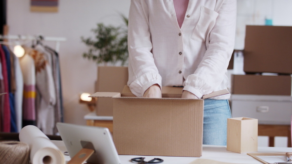 Unrecognizable young woman dropshipper with tablet working at home, coronavirus concept.