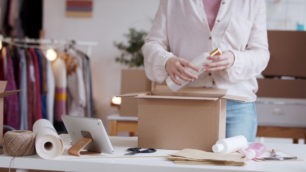 Unrecognizable young woman dropshipper with tablet working at home, coronavirus concept.