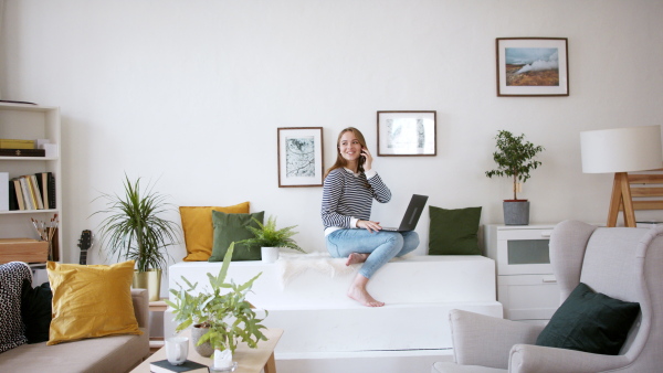 Young woman student with laptop and smartphone working at home, coronavirus concept.