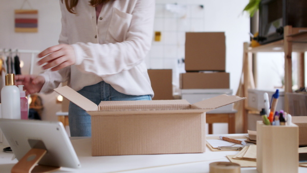 Unrecognizable young woman dropshipper with tablet working at home, coronavirus concept.