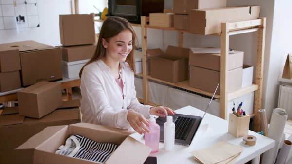 Young woman dropshipper working at home and packing an order, coronavirus concept.