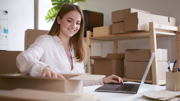 Young woman dropshipper with laptop working at home, coronavirus concept.