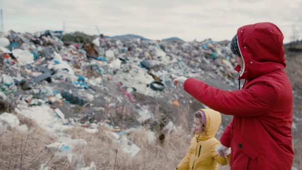 Father with small daughter activist standing on landfill, environmental concept. Slow motion.