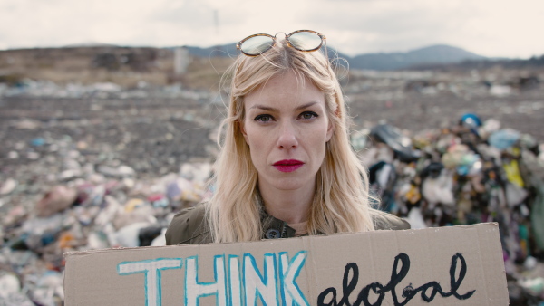 Woman activist holding placard poster on landfill, environmental pollution concept.