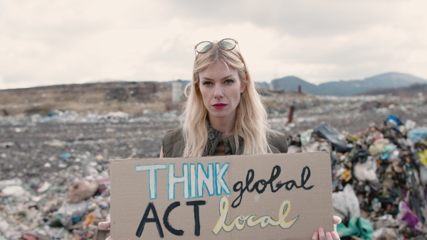 Woman activist holding placard poster on landfill, environmental pollution concept.