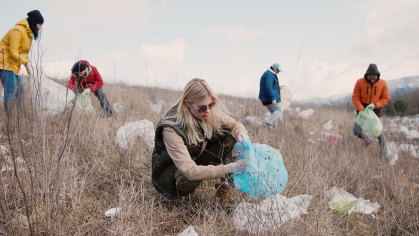 Group of activists picking up litter in nature, environmental pollution and plogging concept.