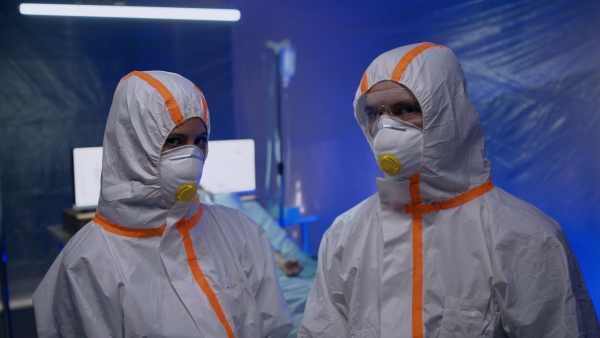 Doctors with protective suit and mask looking at camera in hospital, coronavirus concept.