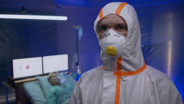 Doctor with protective suit and mask looking at camera in hospital, coronavirus concept.