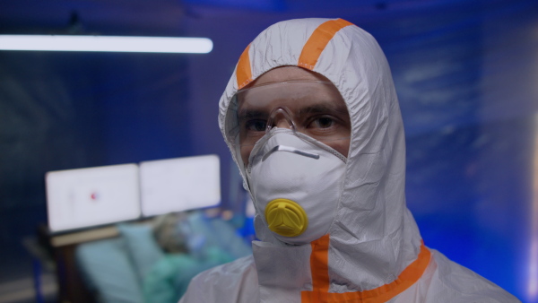 Doctor with protective suit and mask looking at camera in hospital, coronavirus concept.