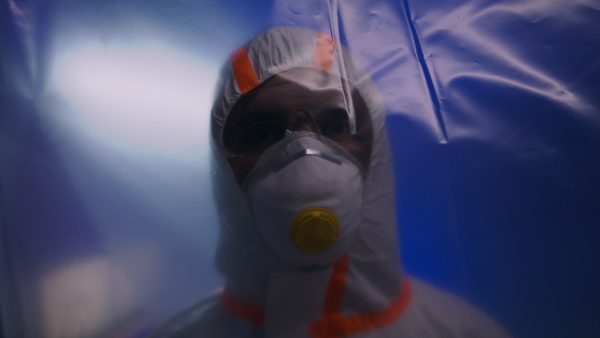 Doctor with protective suit and mask looking at camera in hospital, coronavirus concept.