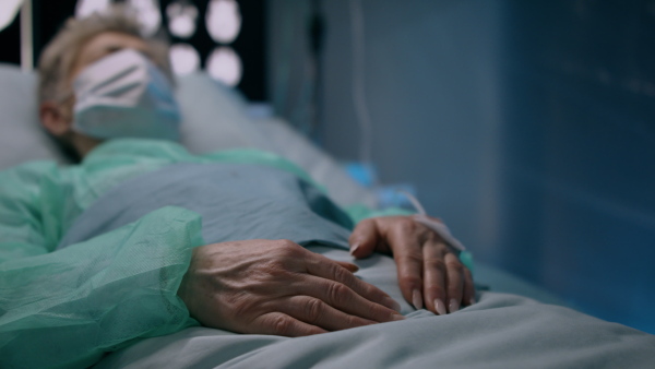 Senior infected patient in quarantine lying in bed in hospital, coronavirus concept.