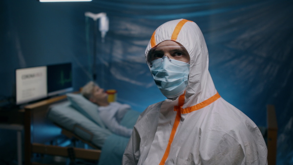 Doctor with protective suit and mask looking at camera in hospital, coronavirus concept.