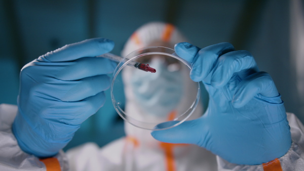 Doctor with protective suit and mask analyzing blood samples, coronavirus concept.