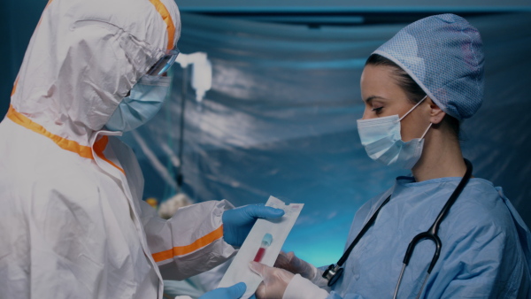 Doctors taking blood samples of patient in hospital, talking. Coronavirus concept.