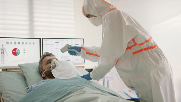 Doctor measuring temperature of infected patient in hospital, coronavirus concept.