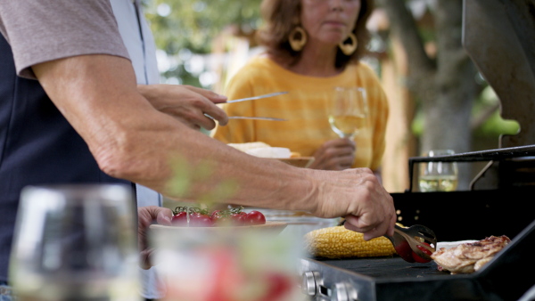 Large family having a garden party, close up on father with son barbecuing.