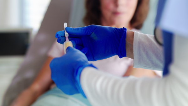 Midsection of unrecognizable doctor with patient in bed in hospital, giving injection.