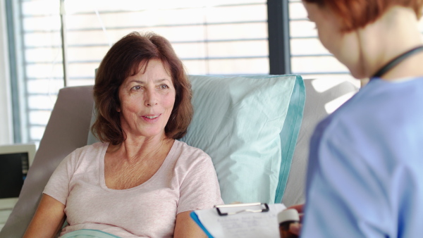 A female doctor talking to patient in bed in hospital about taking medication.