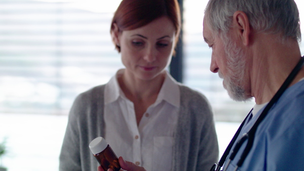 Woman talking to senior doctor in hospital about taking medication.