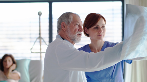 Doctors standing in hospital room, examining lungs X-ray.