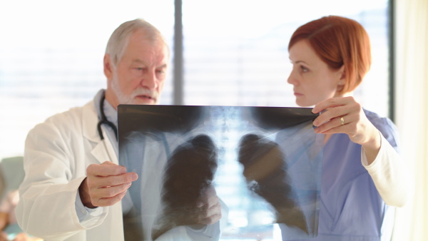 Doctors standing in hospital room, examining lungs X-ray.