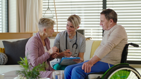 Healthcare worker visiting senior patient in wheelchair at home, talking about taking medication.