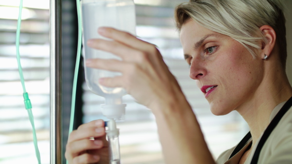 Portrait of nurse preparing IV drip in hospital or at home, close-up.