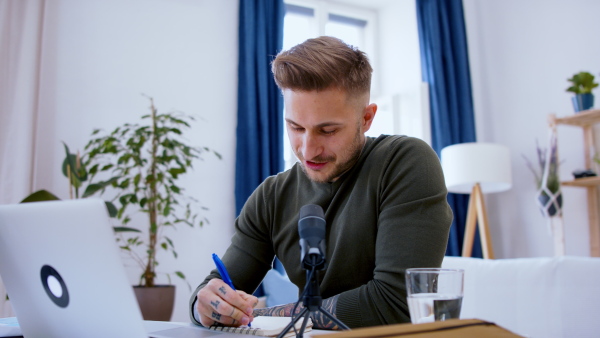 Front view of man with laptop working indoors at desk in home office, video call concept.