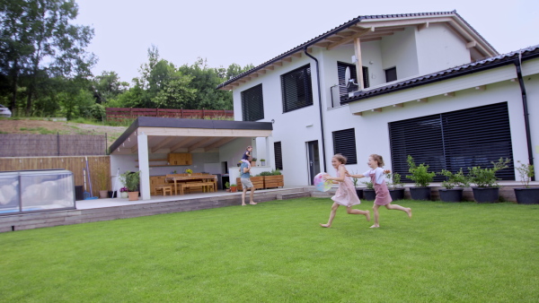 A father with daughters playing outdoors in the backyard, running.