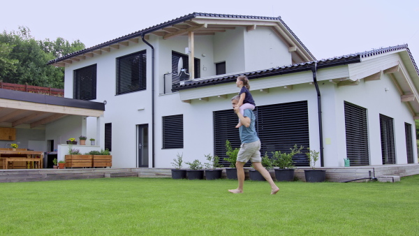 A father with daughters playing outdoors in the backyard, running.