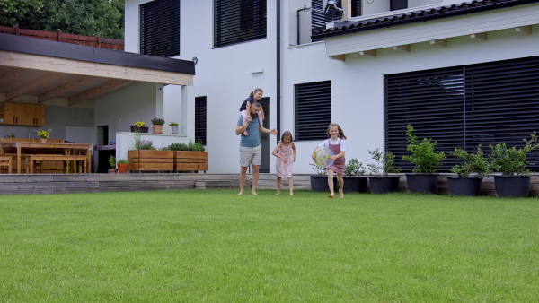 A father with daughters playing outdoors in the backyard, running.