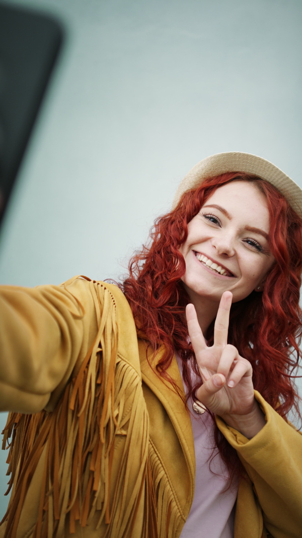 A vertical footage of young woman tourist outdoors against white background on trip in town, taking selfie.