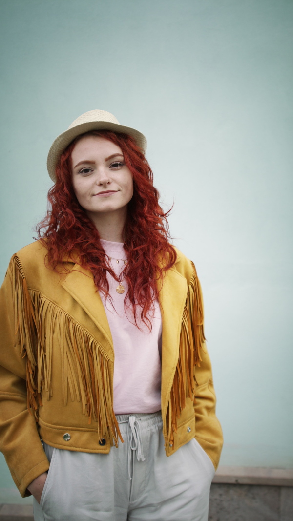 A vertical footage of young woman tourist outdoors against white background on trip in town, looking at camera.