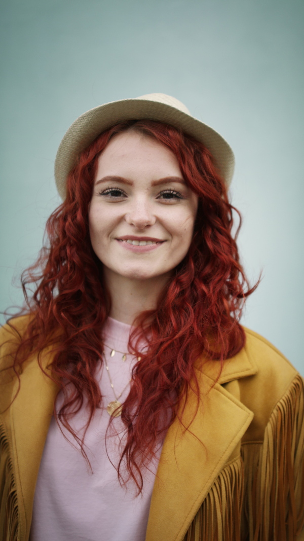 A vertical footage of young woman tourist outdoors against white background on trip in town, looking at camera.