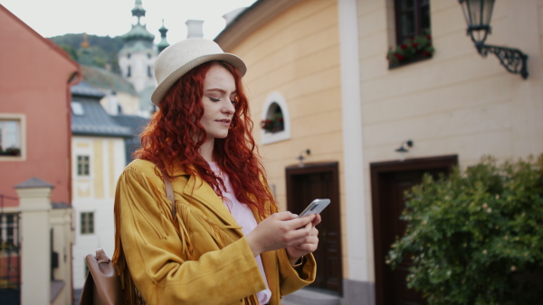 A young woman outdoors on trip in town, using online map on smartphone.