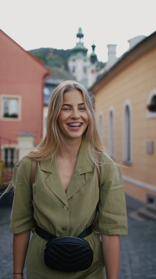 Vertical footage of happy young woman tourist outdoors on trip looking at camera.