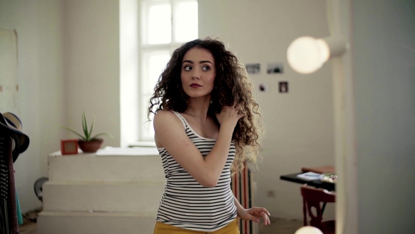 A young teenage girl looking in the mirror indoors. Slow motion.